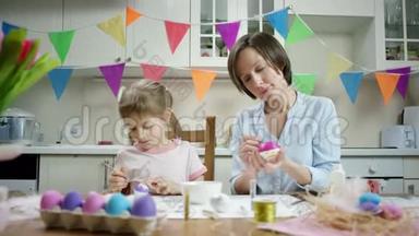 母女俩坐在餐桌旁，一起用彩蛋做窝，在厨房里干活