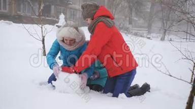 父母和孩子在雪地里玩耍。 妈妈和两个女儿在冬天堆雪人。