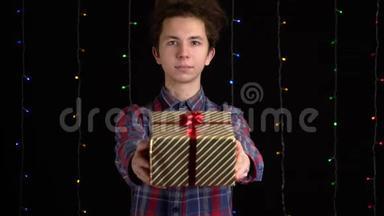 带黑背景礼盒的男孩。 新年快乐、圣诞快乐、情人节礼品盒