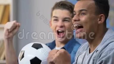 两个兴奋的青少年庆祝最喜欢的球队<strong>进球</strong>，在电视上看足球比赛