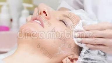 美容师在客户脸上擦奶油`做美容手术，在美容过程中脸部