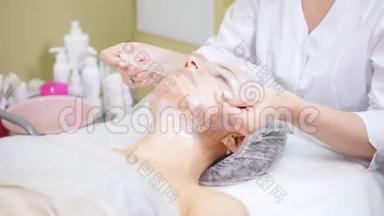 美容师在美容诊所做美容手术，`客户的脸颊做面部清洁。