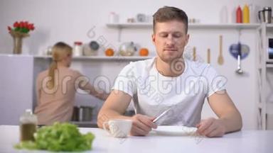 积极的男人等待晚餐，年轻的妻子在背景上<strong>煮汤</strong>，饥饿