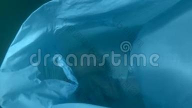 塑料污染，一个废弃的蓝色塑料袋在水下漂流，里面有水母。 水母被困在塑料袋里。