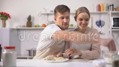快乐的一对夫妇笨拙地揉着面团，在厨房里一起度过快乐的时光