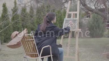 熟练的艺术家在后院的画布上画画。 美丽热情的女孩从事创造力。 <strong>启示</strong>