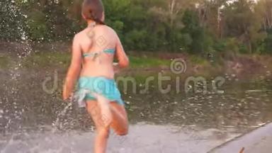 快乐的孩子们沿着海滩奔跑。 女孩们在沙滩上奔跑，在海滩上溅起水滴，笑着。 快乐和快乐