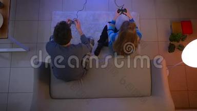 一对年轻夫妇穿着睡衣玩电子游戏，女孩在客厅赢了，而男孩在客厅输了。