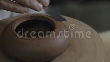 陶工用木轴上的金属抹子从宜兴粘土上加工茶壶。 茶叶手工粘土茶壶