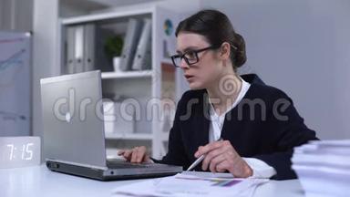 办公室女雇员在笔记本电脑和文件中查阅资料，工作