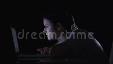 女孩在笔记本电脑上滚动社交网络，微笑着阅读帖子和信息