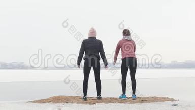 两个穿<strong>着</strong>夹克的苗条女人在雪地海滩上<strong>蹲着</strong>弯腰