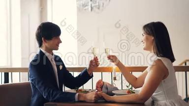 可爱的情侣女孩和男孩在<strong>餐厅</strong>的浪漫<strong>约会</strong>中谈笑风生地捧着酒杯和起泡葡萄酒