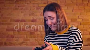使用游戏控制台娱乐坐在沙发上玩电子游戏的年轻快乐女孩的特写肖像。