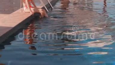 少年少女在度假酒店的游泳池里游泳。 坐在泳池边上的少女