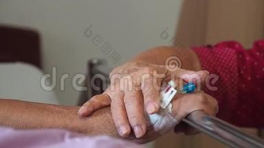 妻子在医院探望丈夫。 这对老夫妇牵着双手躺在病床上住院治疗，以支持他亲爱的。