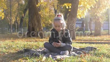 年轻女孩戴着耳机听音乐，在秋天的城市公园里唱最喜欢的歌。 女孩是个了不起的人