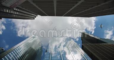 仰望下城区的摩天大楼商务大楼，飞机飞过天空中翻滚的城市云