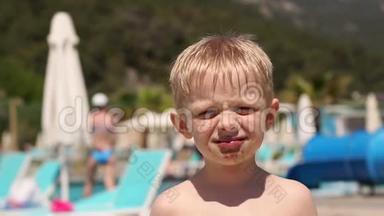 一个小<strong>孩子</strong>在<strong>暑假</strong>在游泳池附近吃巧克力冰淇淋。