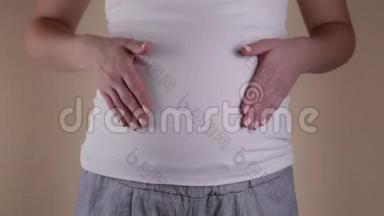 一个穿着睡衣的年轻孕妇的真实特写镜头正在抚摸她早上刚醒来的腹部。