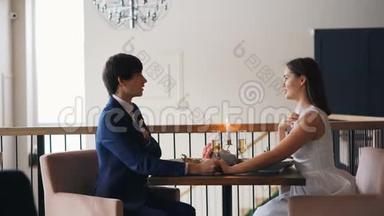 有爱心的年轻人正在餐厅里和一个快乐的女孩求婚，她坐在桌旁，给她戒指