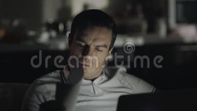 特写镜头集中了一个深夜在家里用笔记本电脑工作的人。