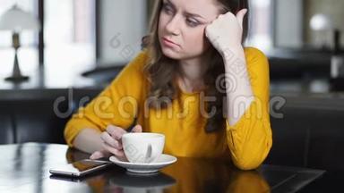 女人独自坐在咖啡馆里，在电话里查看<strong>留言</strong>，男朋友约会迟到了