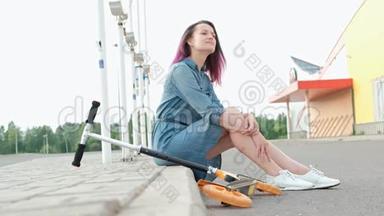 迷人的年轻女人，染了头发，穿着<strong>牛仔裙</strong>和白色运动鞋，坐在路边休息。