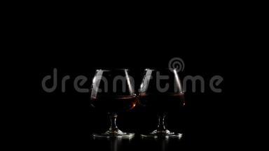 豪华白兰地。 两杯金色干邑，黑色背景的黑桌上。 光线照在桌子上，玻璃。