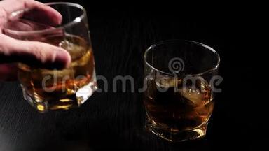 豪华威士忌。 手拿着一杯金色威士忌和真正的冷冰从黑桌上。 不倒翁威士忌。 波旁酒。
