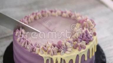 女人`手在木头背景上用紫色奶油切蛋糕。 紫色蛋糕。 顶部视图