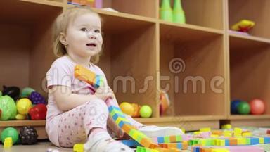 一个小女孩在幼儿园玩乐高积木，拿起一个高塔的细节，打破它，并放置塔。