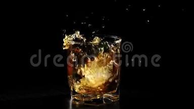豪华威士忌。 冰块落在一杯威士忌中，溅在黑色的桌子上，背景是黑色的。 苏格兰威士忌。