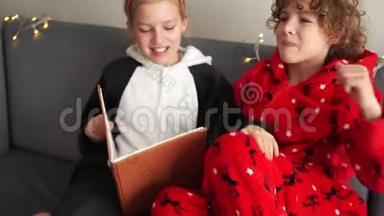 圣诞睡衣快乐的孩子们在圣诞节前的晚上读了一本书。 家庭幸福新年快乐