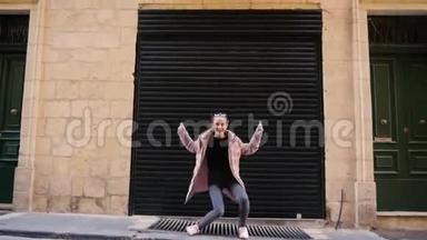 有趣的少女穿着<strong>羽绒服</strong>在城市车库的背景下跳舞。 街头，人们，平凡的日子