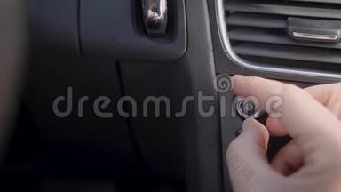 人在调节车内收音机的音量，控制面板上的旋转手柄，手的特写