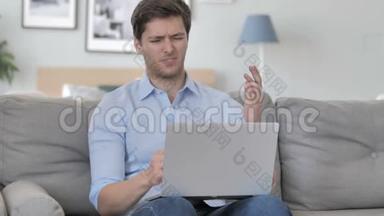 沮丧的老人在坐在沙发上用笔记本电脑面对损失