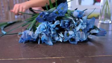 花店女店员用桌上的蓝色鸢尾花制作花束在店里出售。