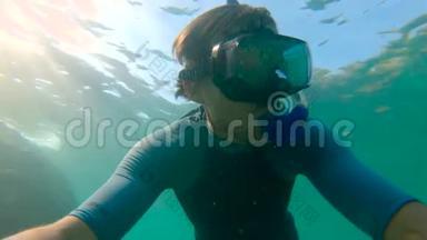 一个年轻人浮潜和潜水潜入海里的慢动作镜头。 一件衬衫袖子上的U.F50-表明