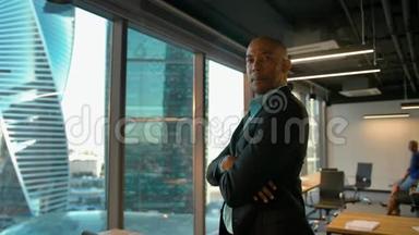 美国黑人企业家站在巨大的现代办公室窗口附近，表情严肃