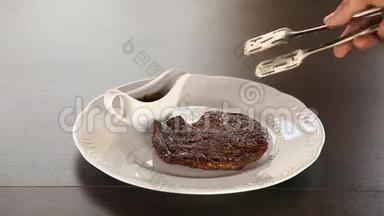 厨师把牛肉排放在盘子里，用草药装饰，用橄榄油泼洒