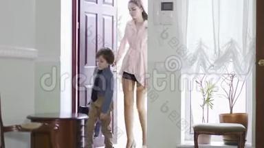 小女孩打开一扇门，带着疲惫的弟弟回家，他背着大书包。 作为成年人的孩子。 一个