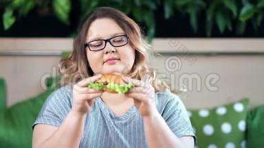 喜笑颜开的胖胖女人吃着开胃的汉堡看着镜头的画像