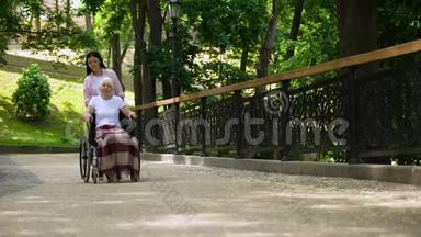 孙女把老妇<strong>人推</strong>在<strong>轮椅</strong>医院的花园里，支持和照顾