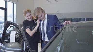快乐的男人和女人刚刚在现代汽<strong>车展</strong>上买了车。 一对夫妇在汽车旁拥抱，开着车门