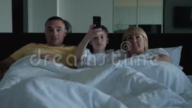一个幸福的家庭。 家人、父母和儿子躺在床上看视频，和亲朋好友聊天