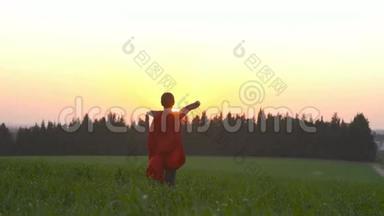 日落时穿着<strong>超级</strong>英雄斗篷的男孩在田野里奔跑