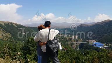 年轻夫妇来到旅游<strong>城市</strong>杰尔穆克，站在山上，手工地互相展示哪些风景如画的地方