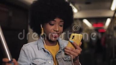 年轻的非洲裔美国妇女在乘坐<strong>公共交通工具</strong>时有一个视频电话。 城市灯光背景。