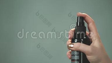 女人按下瓶子上的一个按钮，从那里清漆或<strong>固定</strong>液飞溅。